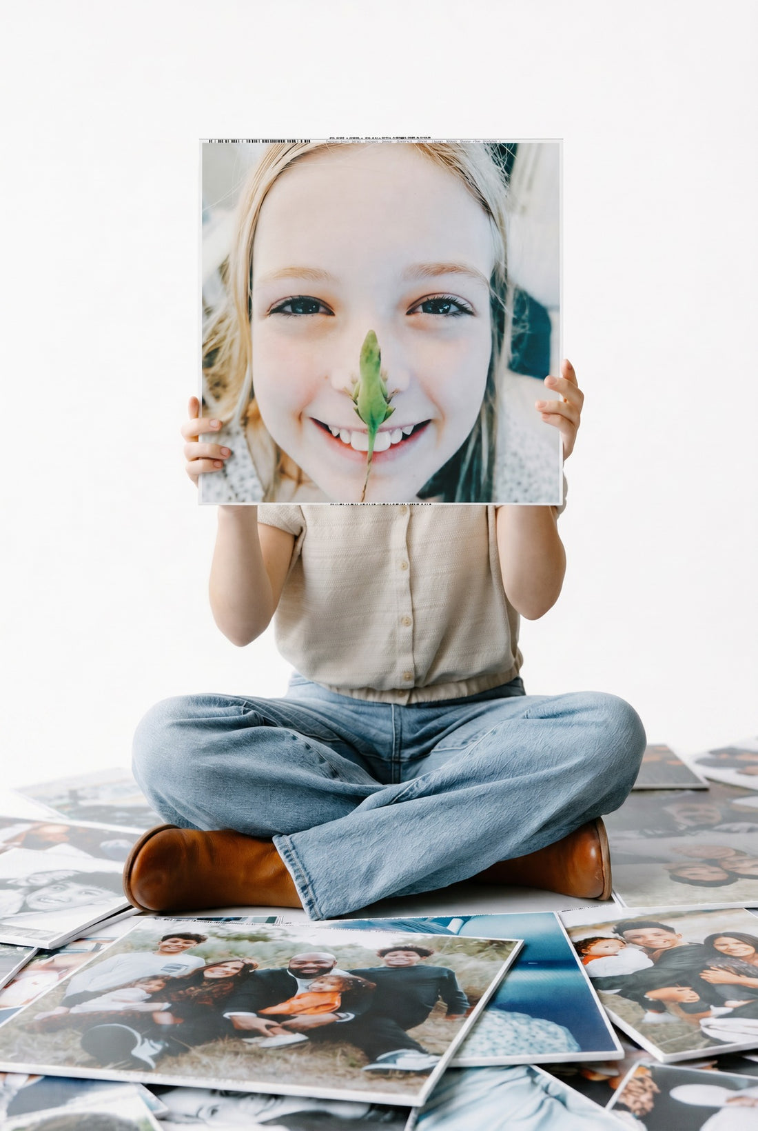 A person holding a portrait print in front of them, with more photo prints at their feet